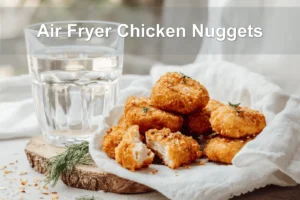 Air Fryer Chicken Nuggets on white napkin with pickles and glass of water