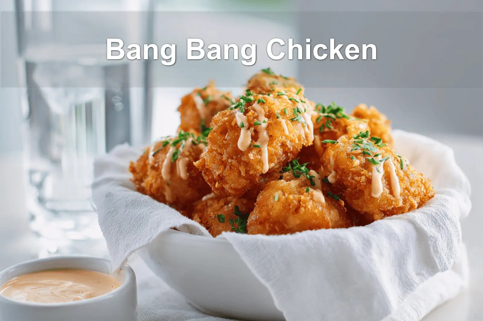 Bang Bang Chicken golden crispy pieces drizzled with sauce and fresh herbs on white cloth