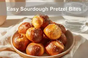 Golden-brown Easy Sourdough Pretzel Bites on white napkin with glass of water beside.