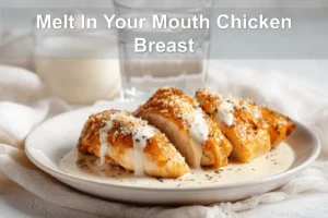 Melt In Your Mouth Chicken Breast plated with creamy white sauce and grated hard cheese warm lighting