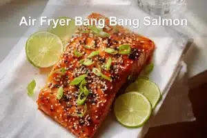 Air Fryer Bang Bang Salmon plated with sesame seeds lime wedges and green onions