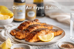 Damn Air Fryer Salmon plated with lemon slices honey soy glaze olive oil bottle beside glass