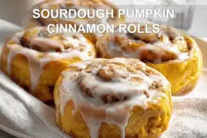 SOURDOUGH PUMPKIN CINNAMON ROLLS glazed rolls on white cloth with clear water glass
