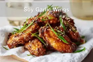 Soy Garlic Wings plated on white napkin with sesame seeds and green onions
