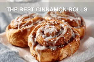 THE BEST CINNAMON ROLLS warm glazed pastries on white cloth with glass of water