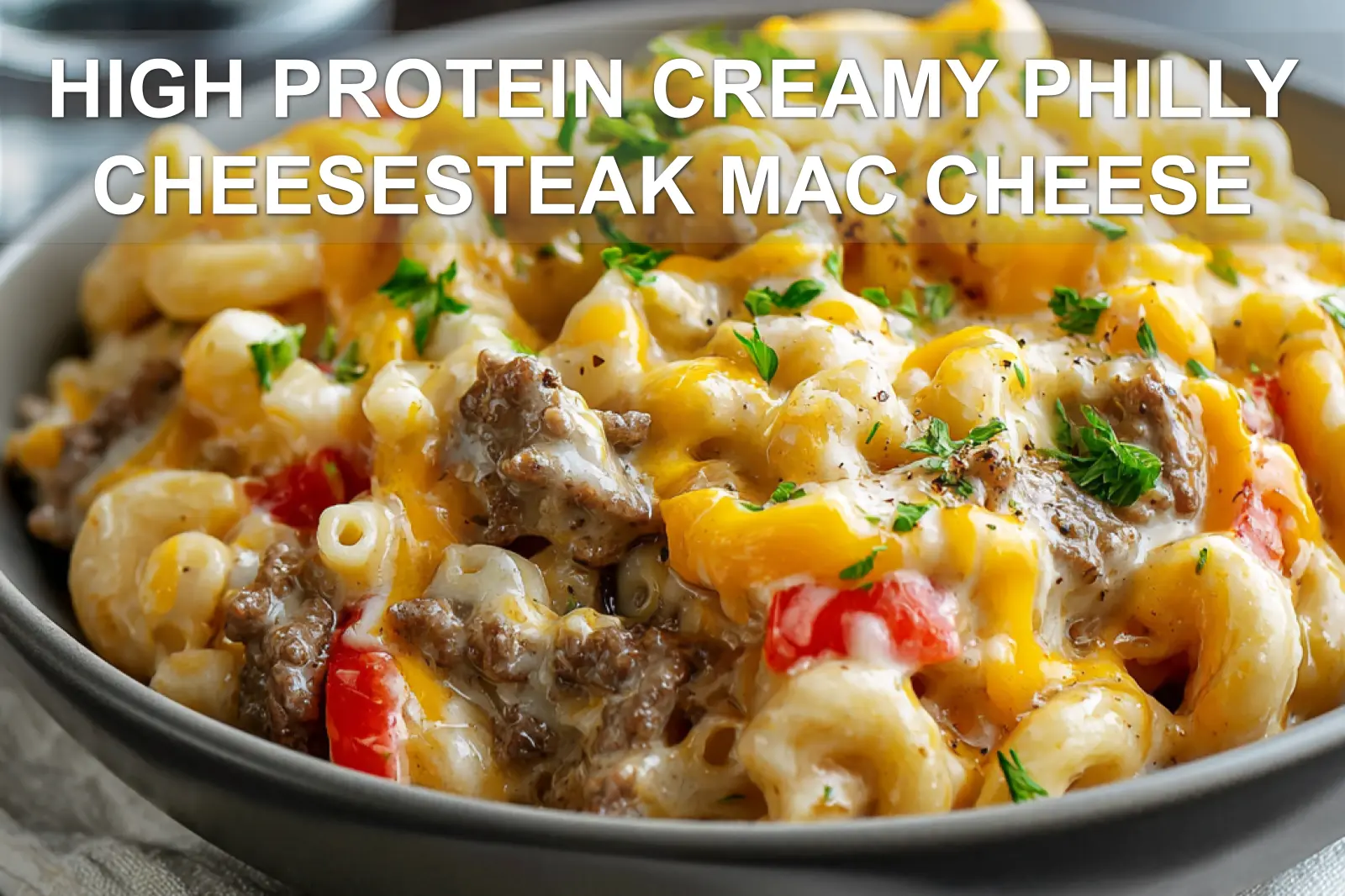 HIGH PROTEIN CREAMY PHILLY CHEESESTEAK MAC CHEESE plated bowl with melted cheese peppers and herbs